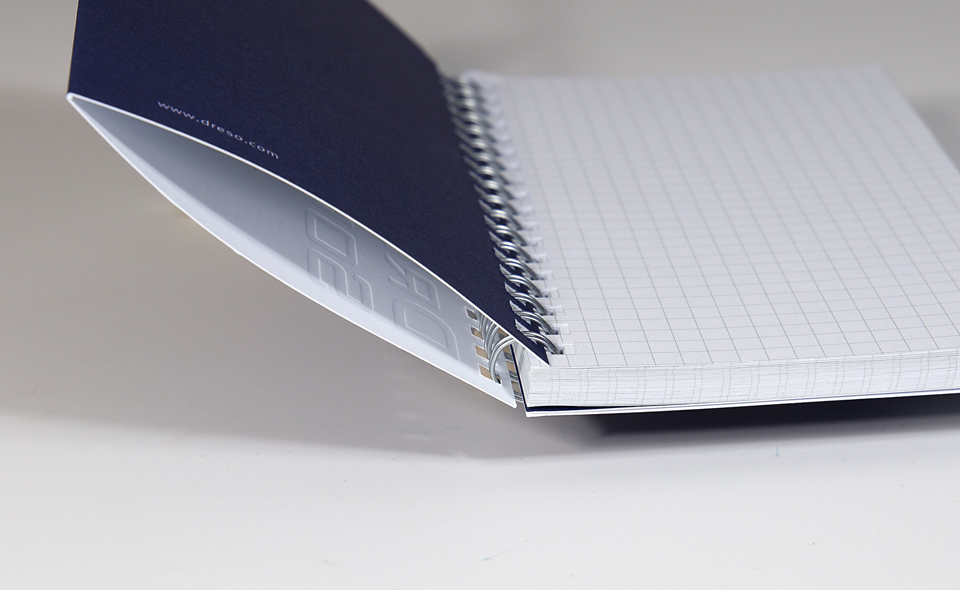 Nahaufnahme eines aufgeschlagenen Notizbuches. Das dunkelblaue Cover besteht aus zwei Papierschichten, dadurch entsteht eine Lasche zwischen den beiden Papieren. 