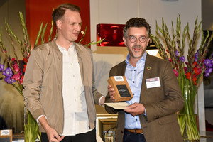 Zwei Männer bei der Preisverleihung. Links Johannes Ehrnsperger, rechts Ralf Lokay, der den Nachhaltigkeits-Preis (viereckig, aus Holz) in den Händen hält. 