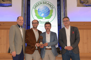 Ralf Lokay und Jonas Muhly nehmen den Green Brands Award entgegen. Im Hintergrund ist groß das "Green Brands" Logo zu sehen. 