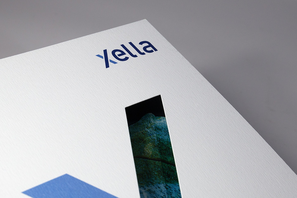 Detailaufnahme von einem Broschüren-Cover der Firma "Xella". Eine Linie des "X" ist ausgestanzt. Detailaufnahme von einem Broschüren-Cover der Firma "Xella". Eine Linie des "X" ist ausgestanzt.