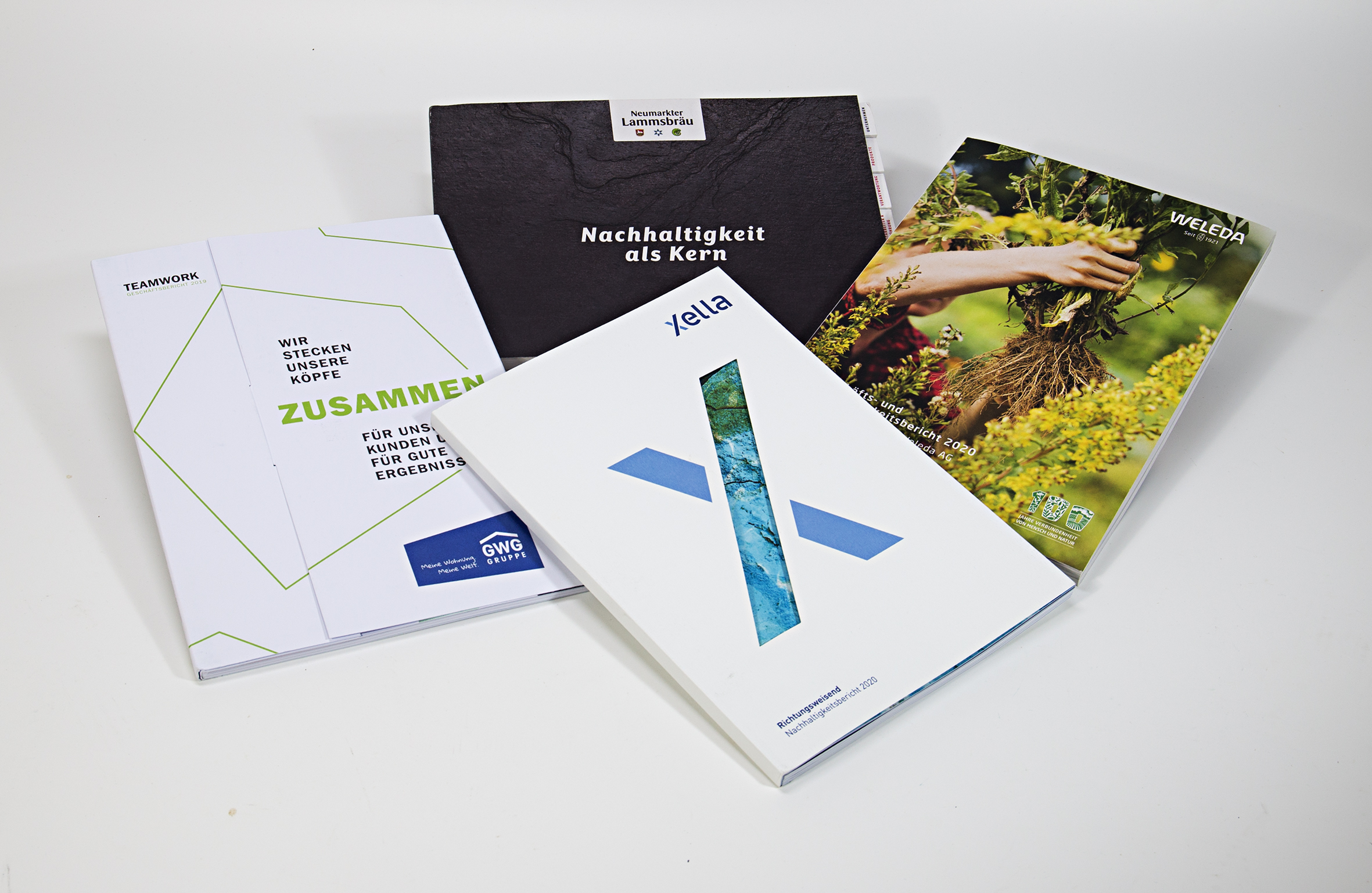 Vier Nachhaltigkeitsberichte, die von uns gedruckt wurden: Neumarkter Lammsbräu, WELEDA, Xella und GWG