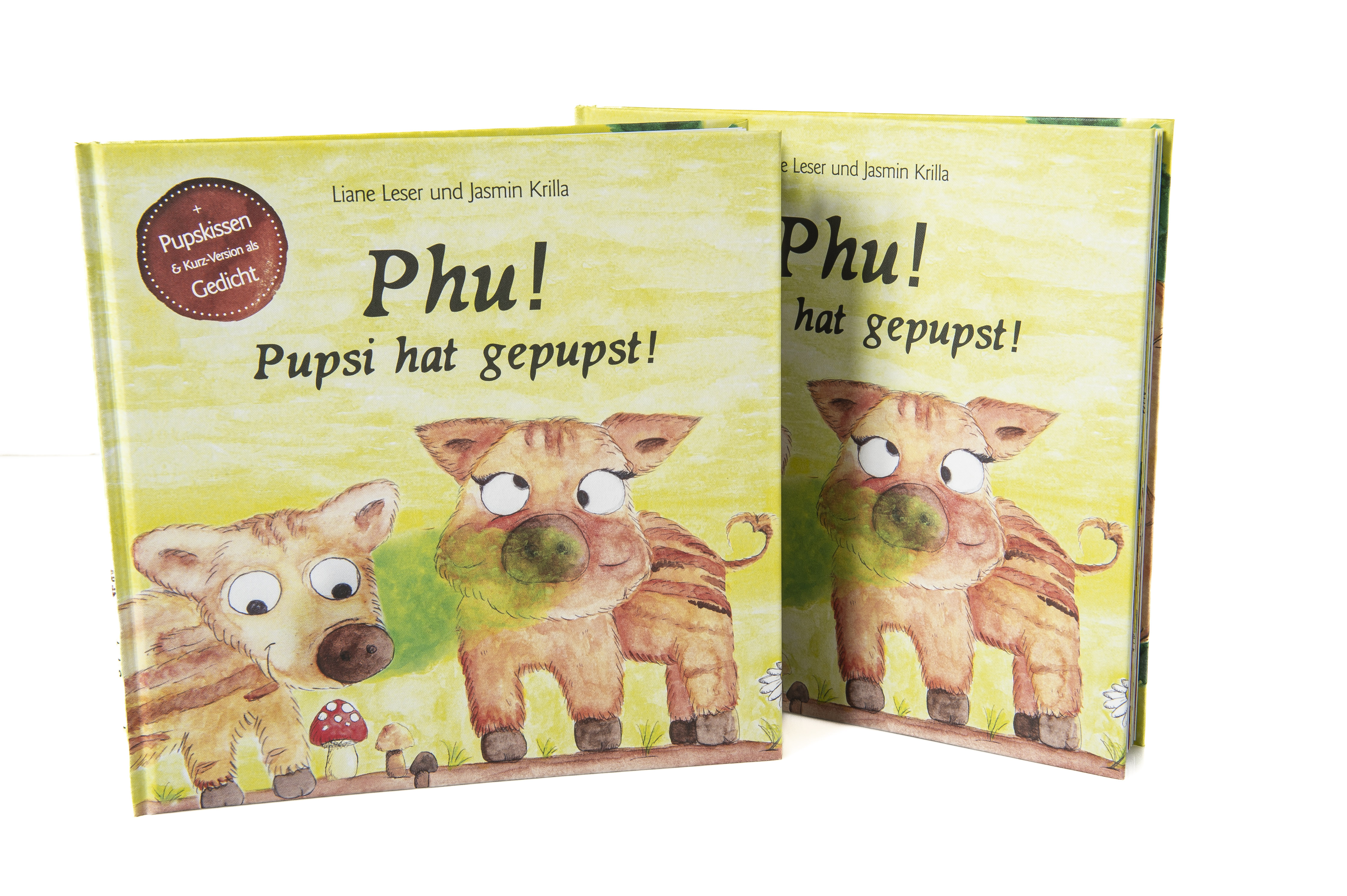 Zwei Exemplare des Buches ""Phu! Pupsi hat gepupst!". Auf dem Cover sind zwei Wildschweine illustriert. Eins verdreht die Augen, vor ihnen ist eine grüne Wolke abgebildet. 